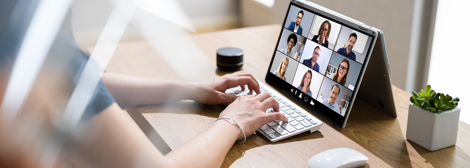 Laptop on a desk with a lots of faces on screen in a meeting